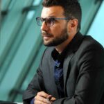 Rodrigo De Vecchi, wearing a dark blazer, hands clasped, mid-discussion.